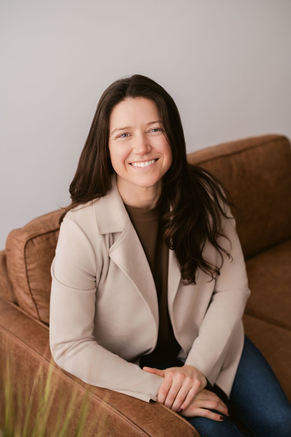 Katlyn Raymond, owner of Sage Cleaning, smiling on a leather sofa